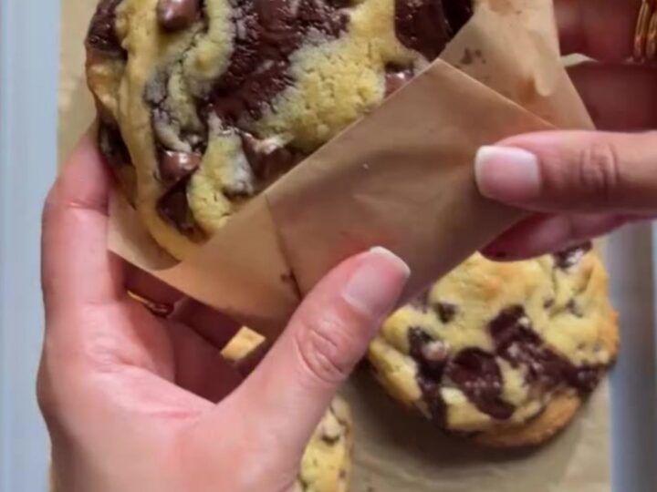 Tall, craggy chocolate chip cookie broken open showing molten chocolate center