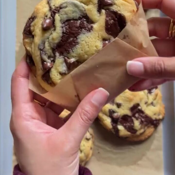 Tall, craggy chocolate chip cookie broken open showing molten chocolate center