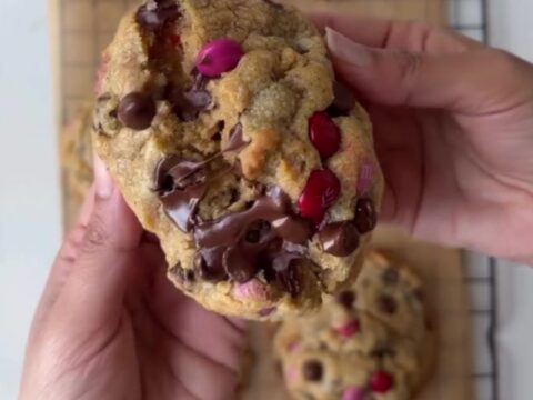 A stack of thick M&M cookies with golden edges and colorful candy pieces
