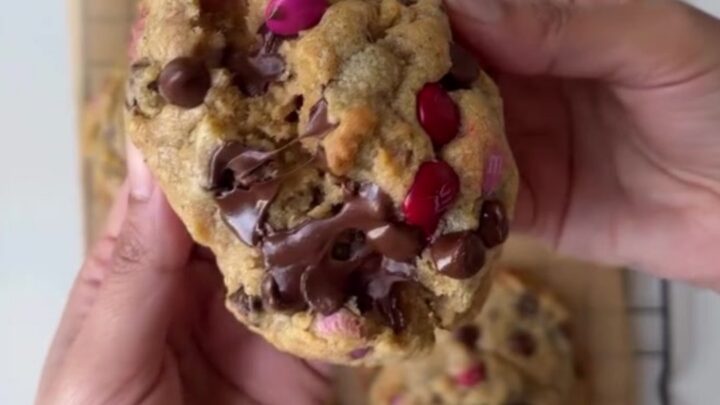 A stack of thick M&M cookies with golden edges and colorful candy pieces