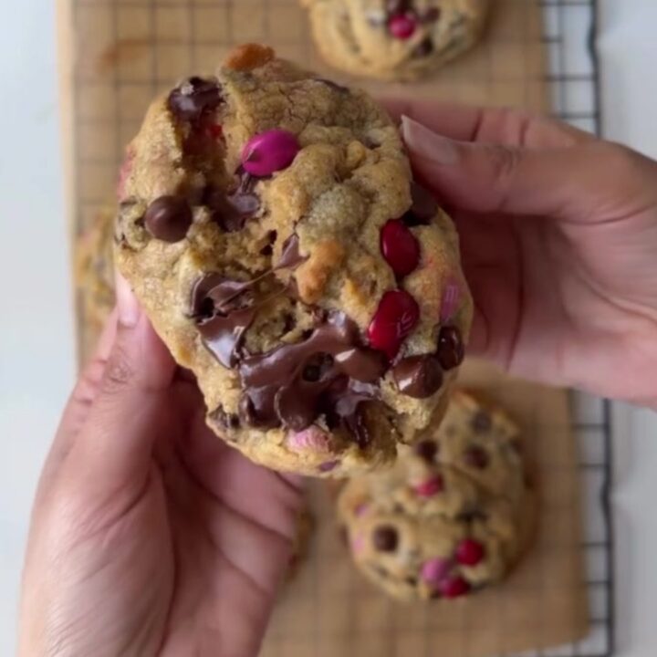 A stack of thick M&M cookies with golden edges and colorful candy pieces