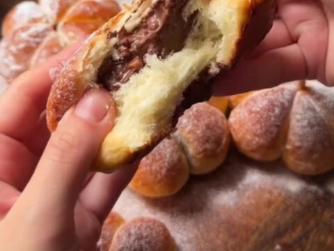 Golden pumpkin-shaped brioche buns with pecan stems on a wooden board, showing melted cheese pull