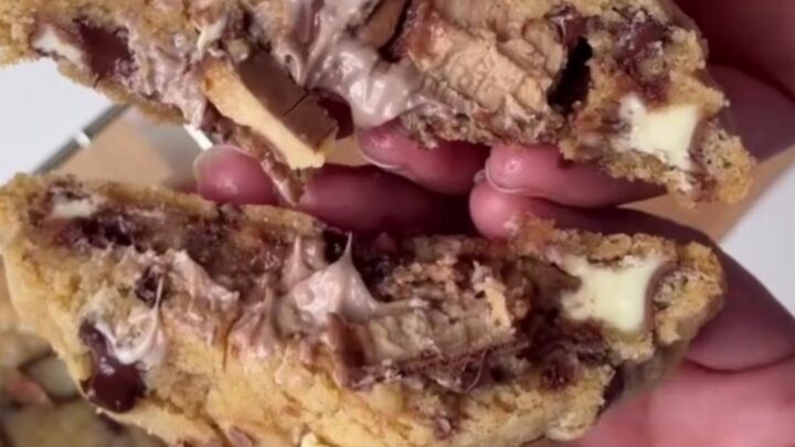 Giant cookie being broken open showing molten hazelnut cream and chocolate flowing out