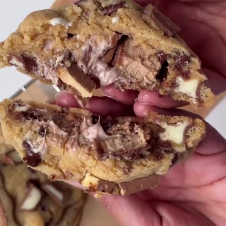 Giant cookie being broken open showing molten hazelnut cream and chocolate flowing out