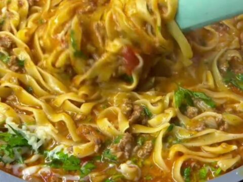 A bowl of tagliatelle with slow-simmered roasted tomato beef ragu, topped with fresh basil and grated parmesan.