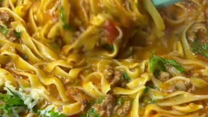 A bowl of tagliatelle with slow-simmered roasted tomato beef ragu, topped with fresh basil and grated parmesan.