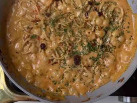 A bowl of spaghetti twirled into a nest, coated in a glossy sauce with caramelized onions and grated parmesan