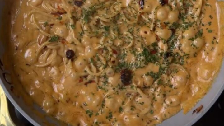 A bowl of spaghetti twirled into a nest, coated in a glossy sauce with caramelized onions and grated parmesan