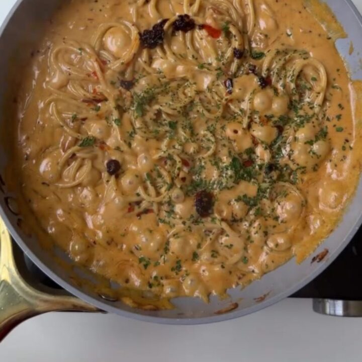 A bowl of spaghetti twirled into a nest, coated in a glossy sauce with caramelized onions and grated parmesan
