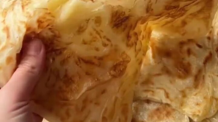 Golden Tokat Katmeri flatbread with visible flaky layers, pulled apart to show steam