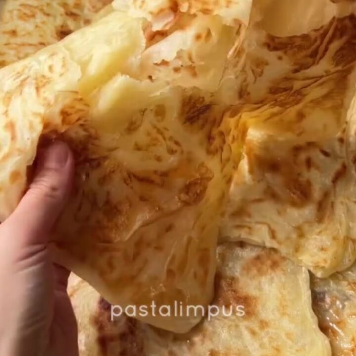 Golden Tokat Katmeri flatbread with visible flaky layers, pulled apart to show steam