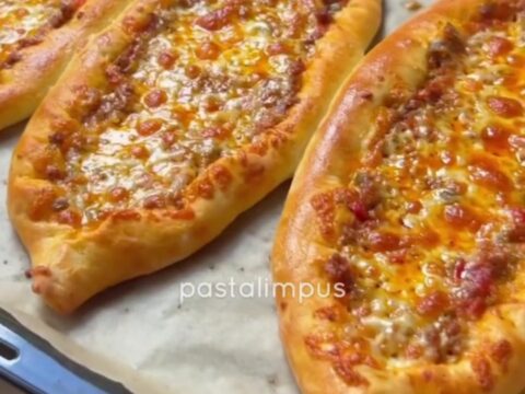 Sliced Turkish boat pide with spiced beef and melted cheese, showing a crispy crust