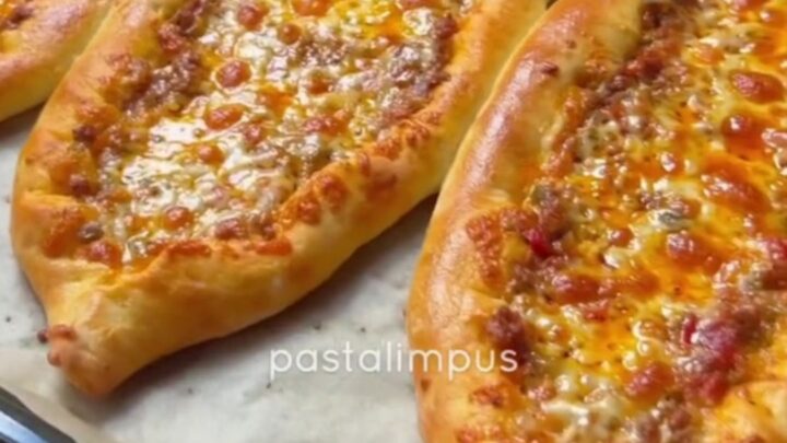 Sliced Turkish boat pide with spiced beef and melted cheese, showing a crispy crust
