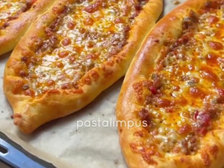 Sliced Turkish boat pide with spiced beef and melted cheese, showing a crispy crust