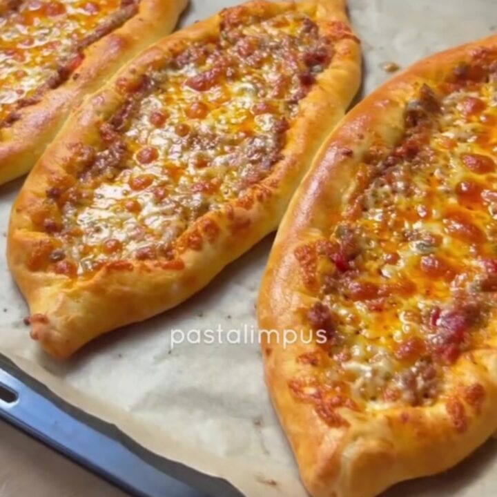 Sliced Turkish boat pide with spiced beef and melted cheese, showing a crispy crust