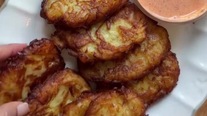 Golden crispy garlic parmesan hashbrowns stacked on a plate with a bowl of spicy mayo for dipping