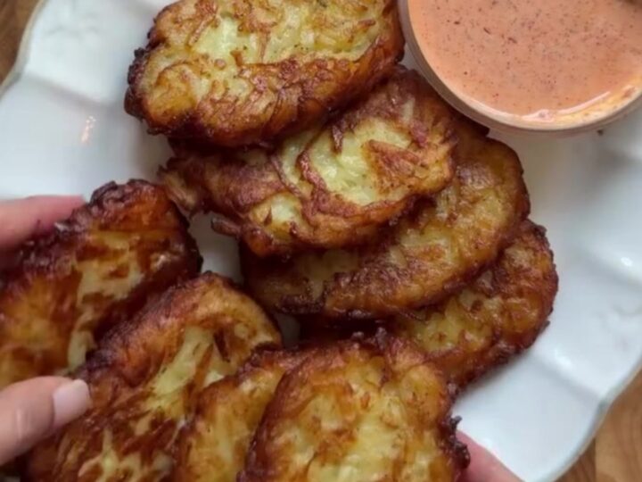 Golden crispy garlic parmesan hashbrowns stacked on a plate with a bowl of spicy mayo for dipping