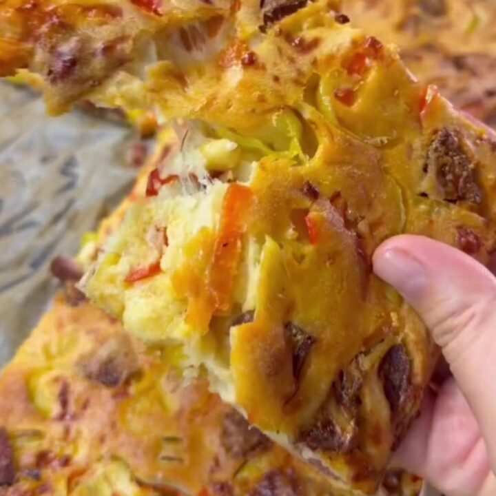 Golden braided crown pizza with sesame seeds and a bowl of marinara in the center.