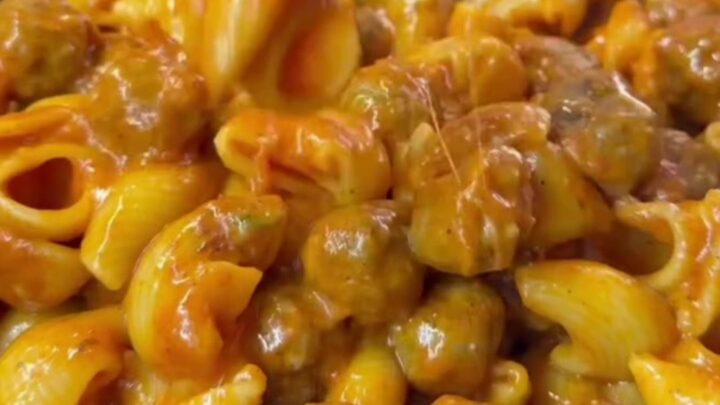 A bowl of Turkish one-pot meatball pasta with penne, mini meatballs, melted cheese, and fresh parsley.
