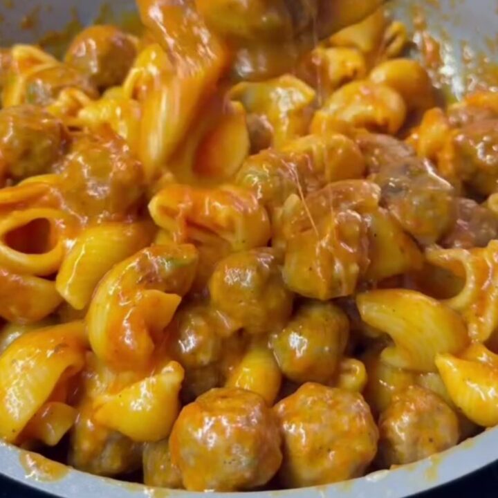 A bowl of Turkish one-pot meatball pasta with penne, mini meatballs, melted cheese, and fresh parsley.