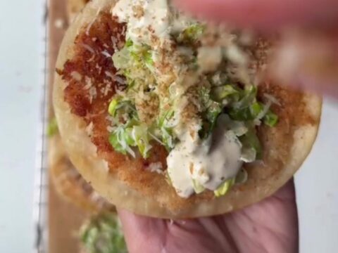 Crispy panko chicken smash tacos topped with Caesar slaw and shaved parmesan, on a wooden board