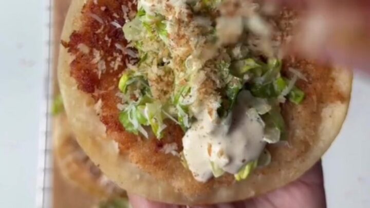 Crispy panko chicken smash tacos topped with Caesar slaw and shaved parmesan, on a wooden board