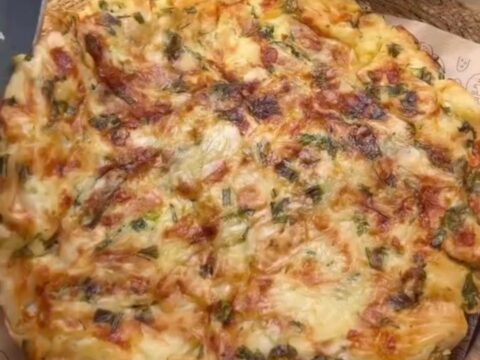 A golden skillet börek with a crackly, layered crust, sliced into wedges, showing melted feta and herbs.