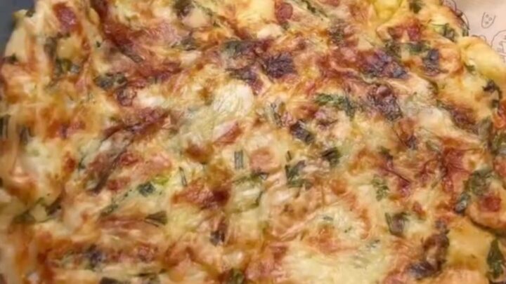 A golden skillet börek with a crackly, layered crust, sliced into wedges, showing melted feta and herbs.