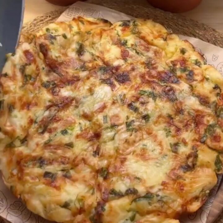 A golden skillet börek with a crackly, layered crust, sliced into wedges, showing melted feta and herbs.