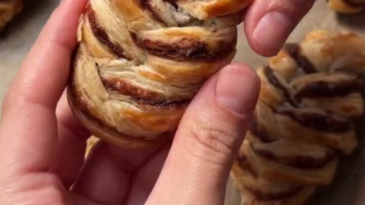 Golden braided puff pastry with melted chocolate oozing from the center, dusted with powdered sugar