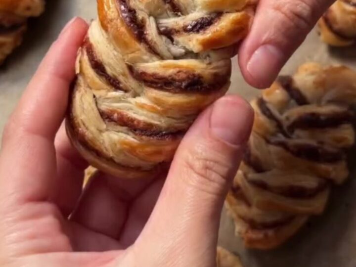 Golden braided puff pastry with melted chocolate oozing from the center, dusted with powdered sugar