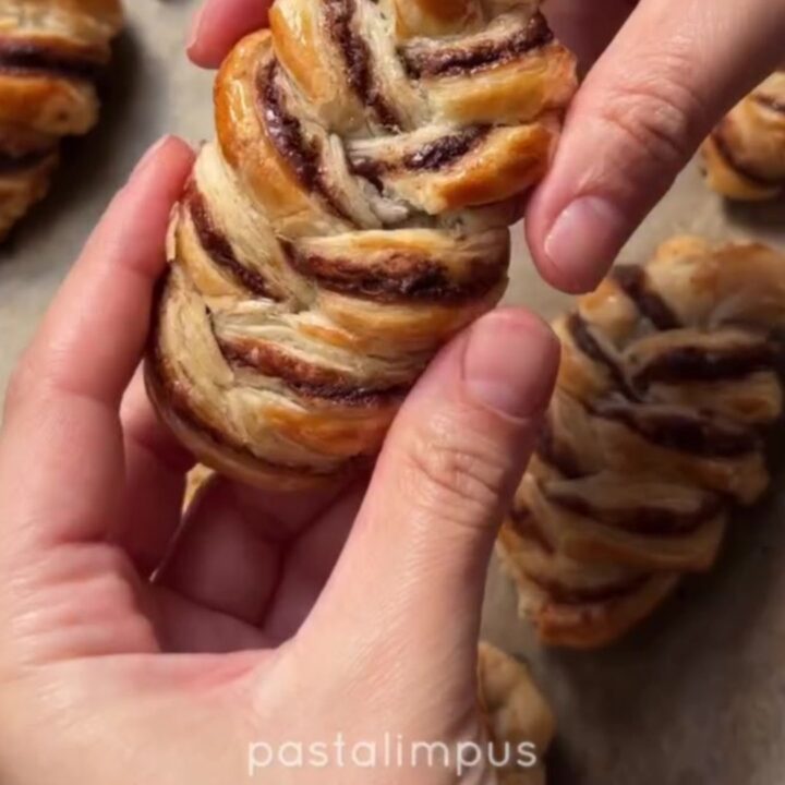 Golden braided puff pastry with melted chocolate oozing from the center, dusted with powdered sugar