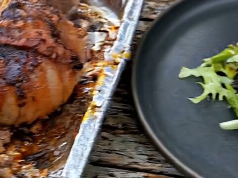 A close-up shot of a bacon-wrapped onion bomb with melting cheese pulling away from the juicy beef center.
