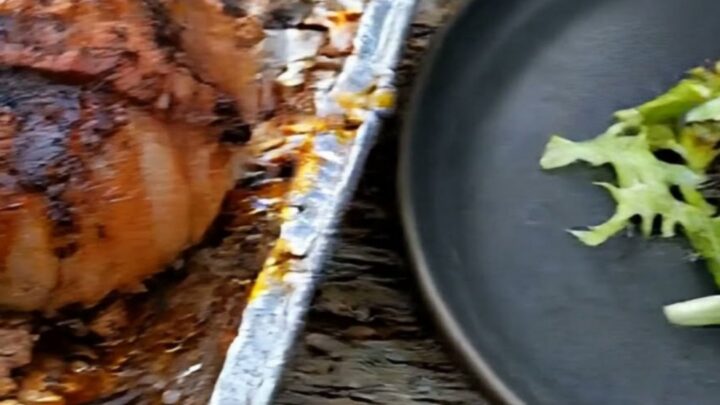 A close-up shot of a bacon-wrapped onion bomb with melting cheese pulling away from the juicy beef center.