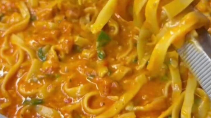 Twirling a forkful of tagliatelle with melted mozzarella and basil in a skillet