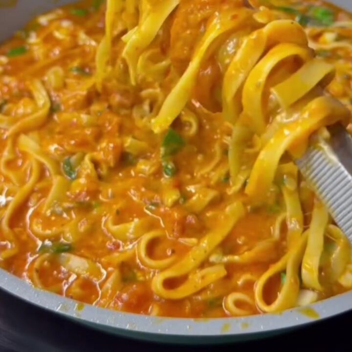 Twirling a forkful of tagliatelle with melted mozzarella and basil in a skillet