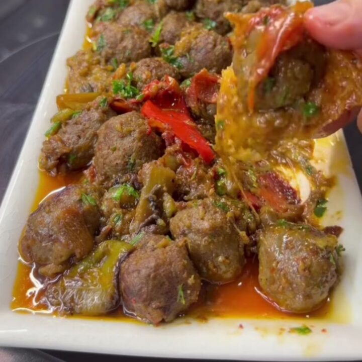 Turkish meatball and roasted eggplant casserole in a baking dish with parsley and crusty bread