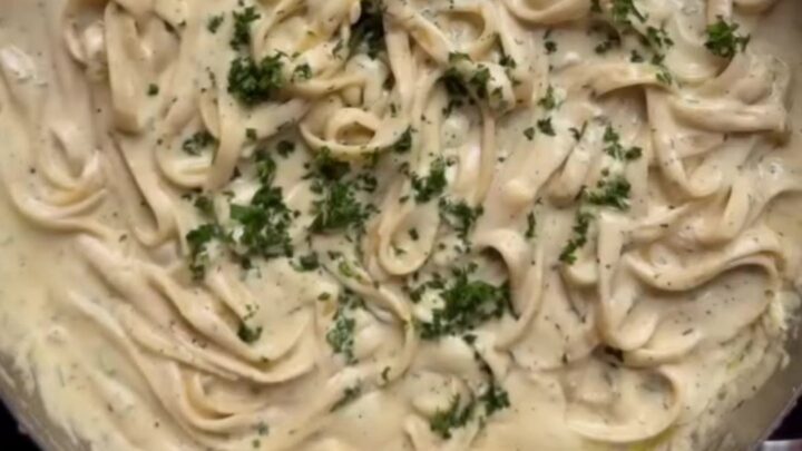 Fettuccine Alfredo in a white bowl with parsley and black pepper