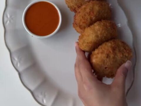 Crispy golden chicken potato croquettes piled on a plate with a bowl of creamy chipotle dip