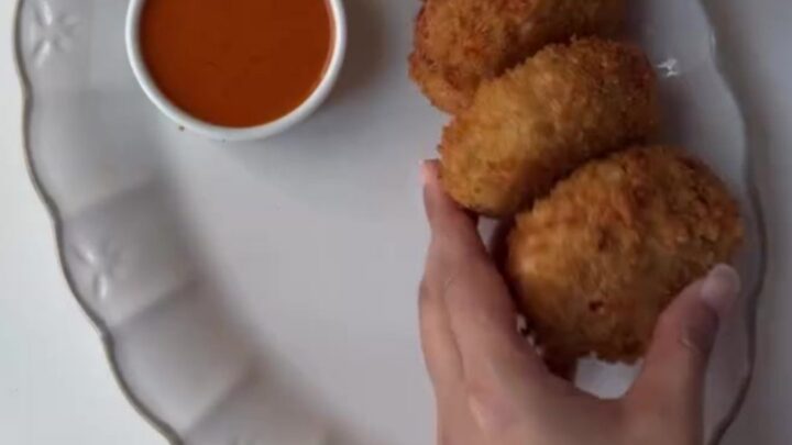 Crispy golden chicken potato croquettes piled on a plate with a bowl of creamy chipotle dip