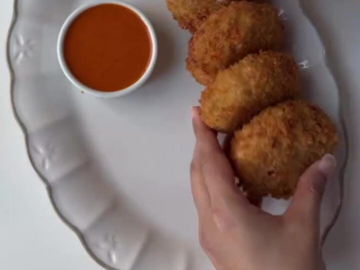 Crispy golden chicken potato croquettes piled on a plate with a bowl of creamy chipotle dip