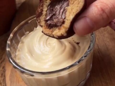A close-up of a tiramisu truffle being snapped in half, showing the creamy espresso center and cocoa-dusted exterior.
