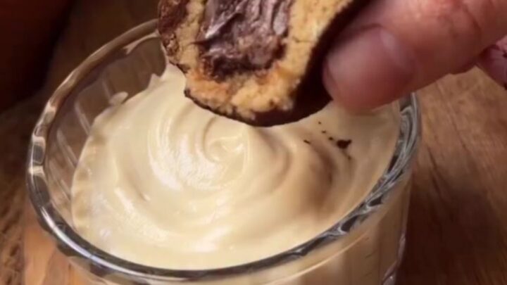 A close-up of a tiramisu truffle being snapped in half, showing the creamy espresso center and cocoa-dusted exterior.