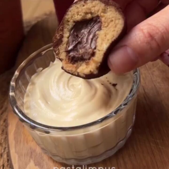 A close-up of a tiramisu truffle being snapped in half, showing the creamy espresso center and cocoa-dusted exterior.