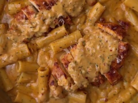 Creamy garlic parmesan chicken pasta with golden chicken cubes and fresh parsley in a large skillet