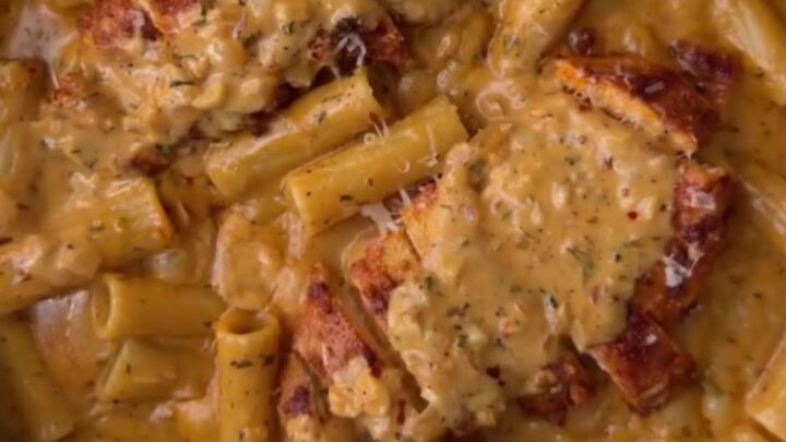 Creamy garlic parmesan chicken pasta with golden chicken cubes and fresh parsley in a large skillet