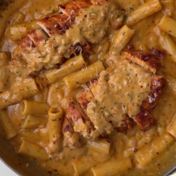 Creamy garlic parmesan chicken pasta with golden chicken cubes and fresh parsley in a large skillet
