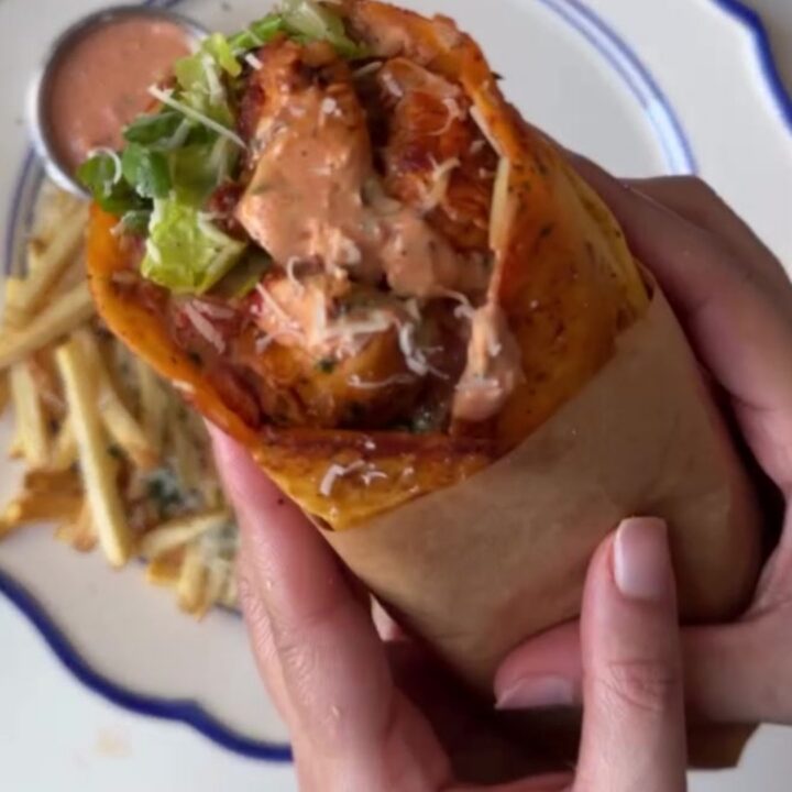 A crispy garlic parmesan chicken wrap cut diagonally, showing melted cheese and chicken, with a side of garlic mayo.