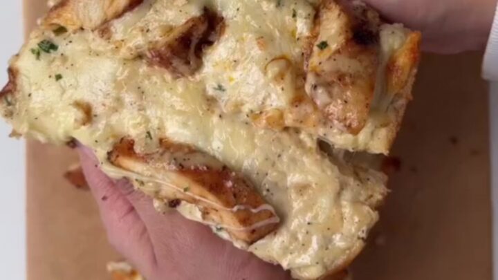 Golden garlic bread with blistered mozzarella and cheddar, pulled apart showing cheese stretch