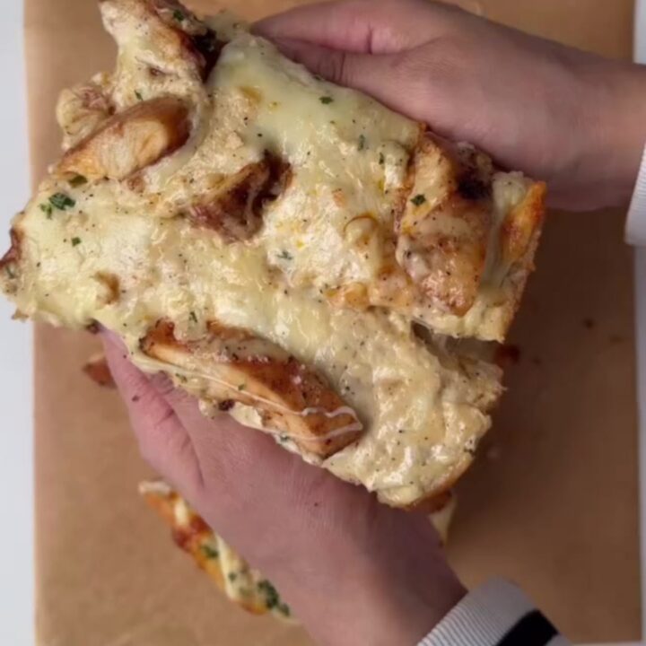 Golden garlic bread with blistered mozzarella and cheddar, pulled apart showing cheese stretch
